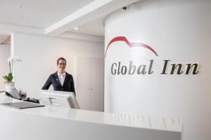 een man aan een bureau in een appelkantoor bij Hotel Global Inn in Wolfsburg