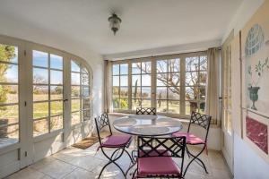 a room with a table and chairs and windows at La Maison des Roches in Gordes
