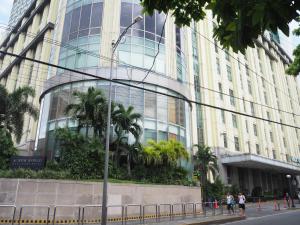 a tall building with palm trees in front of it at Suites de Marina Manila with Netflix in Manila