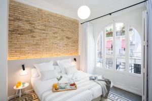 1 dormitorio con cama blanca y pared de ladrillo en SingularStays Parque Central en Valencia