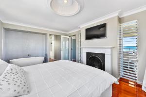 ein Schlafzimmer mit einem weißen Bett und einem Kamin in der Unterkunft Aloha Waterfront Properties in Robe