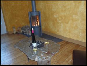 a wine bottle and two glasses on a table with a fireplace at Chambres d'hôtes La Rêvaillante in Bourges