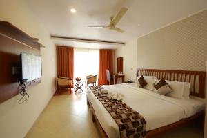 Habitación de hotel con cama grande y TV en Park regency, en Angamaly