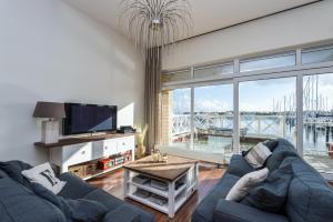 a living room with a blue couch and a large window at Appartement in Zeeland - Kabbelaarsbank 405 - Port Marina Zélande - Ouddorp - not for companies in Ouddorp
