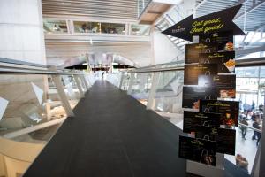 a long walkway in a building with a sign at Tulip Inn Eindhoven Airport in Eindhoven