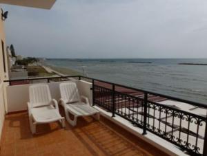 2 sedie bianche sedute su un balcone con vista sull'oceano di Philippou Beach Villas & Apartments a Larnaka