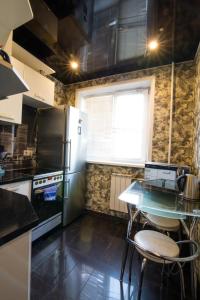 a kitchen with a table and a stainless steel refrigerator at Apartments on Kirova 76 in Novokuznetsk