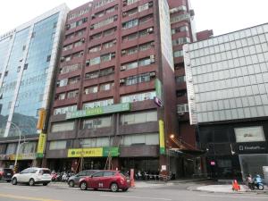 un edificio alto con coches estacionados frente a él en Jung Shin Hotel en Zhongli