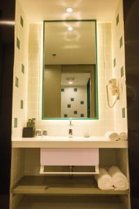 y baño con lavabo, espejo y toallas. en Magnotel Yangshuo West Street, en Yangshuo