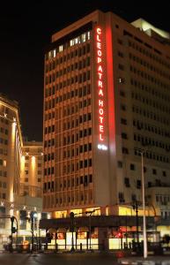 a large building with a red neon sign on it at Cleopatra Hotel in Cairo