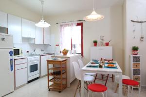 Una cocina con gabinetes blancos y una mesa y sillas blancas. en Protaras Happy Sunny Holidays, en Paralimni