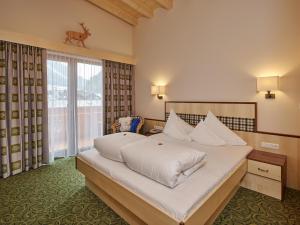 a bedroom with a large bed and a large window at Hotel Gasthof Schöpf in Längenfeld