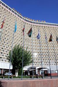 un gran edificio con banderas delante en Hotel Uzbekistan en Tashkent