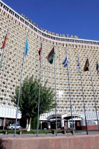 ein großes Gebäude mit Flaggen davor in der Unterkunft Hotel Uzbekistan in Taschkent