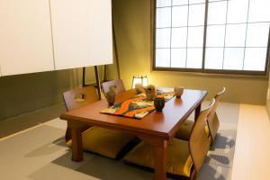 a dining room table with chairs in a room with a window at Kyo-machiya Flower Inn Hanayo in Kyoto