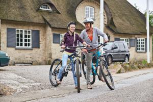 un hombre y una mujer montando bicicletas por una calle en Danhostel Rebild, en Skorping