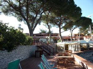 a patio with chairs and tables and trees at Hotel Fiascherino in Lerici