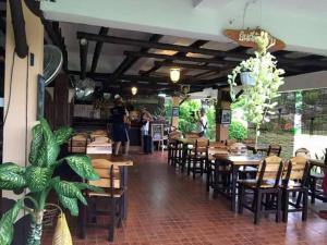 a restaurant with wooden tables and chairs and people at Bamboo House Resort in Kanchanaburi City