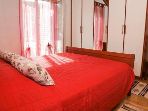 Cama roja con edredón rojo y almohada en Lozna Apartment, en Postira