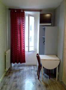 パリにあるオテル デュ セントレのテーブルと赤いカーテン付きの窓が備わる客室です。