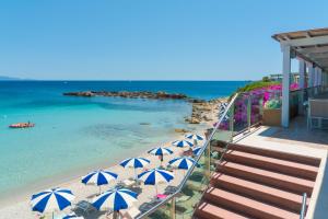 un gruppo di ombrelloni su una spiaggia con l'oceano di Hotel Dei Pini a Fertilia