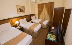 a hotel room with two beds and a television at Anwar Al Zahraa Hotel in Al Madinah