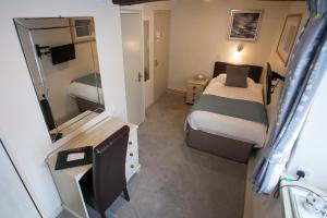 a small bedroom with a bed and a mirror at The Poplars Hotel in Moulton