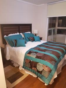 1 dormitorio con 1 cama grande con almohadas azules en Departamento Full en Reñaca-Concon, en Viña del Mar