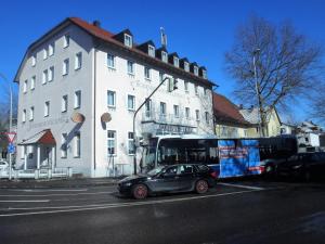 ein Auto, das neben einem Bus vor einem Gebäude parkt in der Unterkunft Bodenseehotel Lindau in Lindau