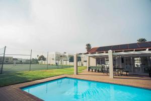 a swimming pool in front of a tennis court at 20 Cayman Beach, Gordon's Bay in Gordonʼs Bay