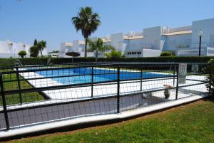 a fence around a swimming pool in front of a building at Apto en Residencial El Bosque in Chiclana de la Frontera