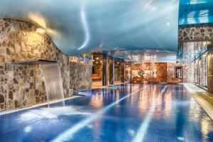 a swimming pool with a waterfall in a building at Wellness Hotel Borovica in Štrbské Pleso