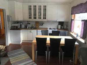 a kitchen with white cabinets and a wooden table and chairs at Kjelkebakken Gard in Lyngseidet