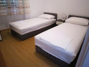 two beds in a room with white sheets at Apartment old town in Primošten