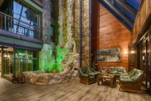 a lobby with a large stone wall with green lights at APLEND Wellness Hotel Borovica in Štrbské Pleso