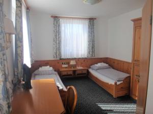 a room with two beds and a desk and a window at Bodenseehotel Lindau in Lindau