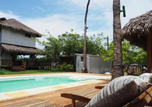 a swimming pool next to a house with a palm tree at Barra Grande Beach Club in Barra Grande