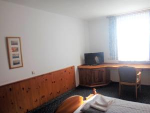 a bedroom with a bed and a desk and a window at Bodenseehotel Lindau in Lindau