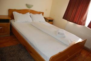 Una cama con sábanas blancas y almohadas en un dormitorio en Pensiunea Rodica en Nădlac
