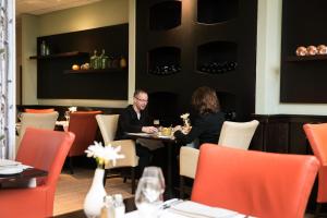 a man and woman sitting at a table in a restaurant at Fletcher Hotel-Restaurant Mooi Veluwe in Putten