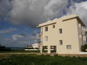 a white building with the ocean in the background at Athena and The Owl Beachside Apt in Paphos