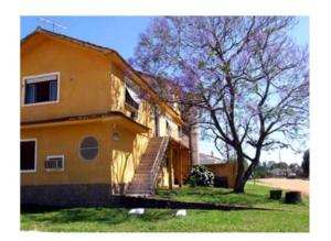 ein gelbes Haus mit einer Treppe neben einem Baum in der Unterkunft Hotel Sao Gabriel in São Gabriel