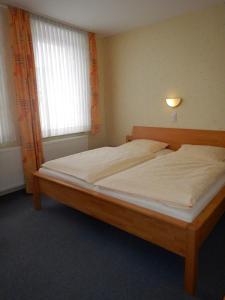 - une chambre avec un lit en bois et des draps blancs dans l'établissement Havergoh Wander- & Fahrrad-Hotel, à Horn-Bad Meinberg