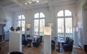 uma sala de jantar com mesas, cadeiras e janelas em L'Esplanade Lille em Lille