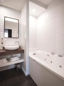 a white bathroom with a tub and a sink at Hôtel Métropole centre ville in Boulogne-sur-Mer