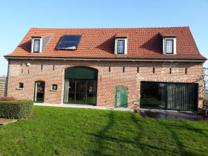 a brick house with a solar roof and a yard at De Prente in Heuvelland