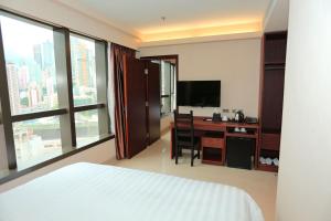 Schlafzimmer mit einem Bett und einem Schreibtisch mit einem TV in der Unterkunft WE Hotel in Hongkong