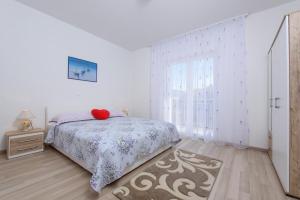 a white bedroom with a bed and a window at Apartments & Rooms Seaside in Kaštela