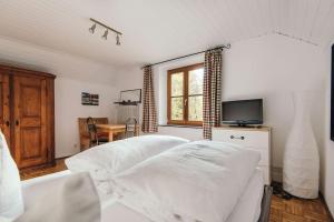 Cette chambre comprend un lit avec des draps blancs et une télévision. dans l'établissement Ferienwohnung am Seidlpark, à Murnau am Staffelsee