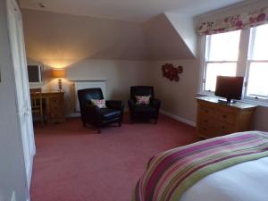 a room with a bed, chair, desk and a lamp at Shaftesbury Hotel Dundee in Dundee
